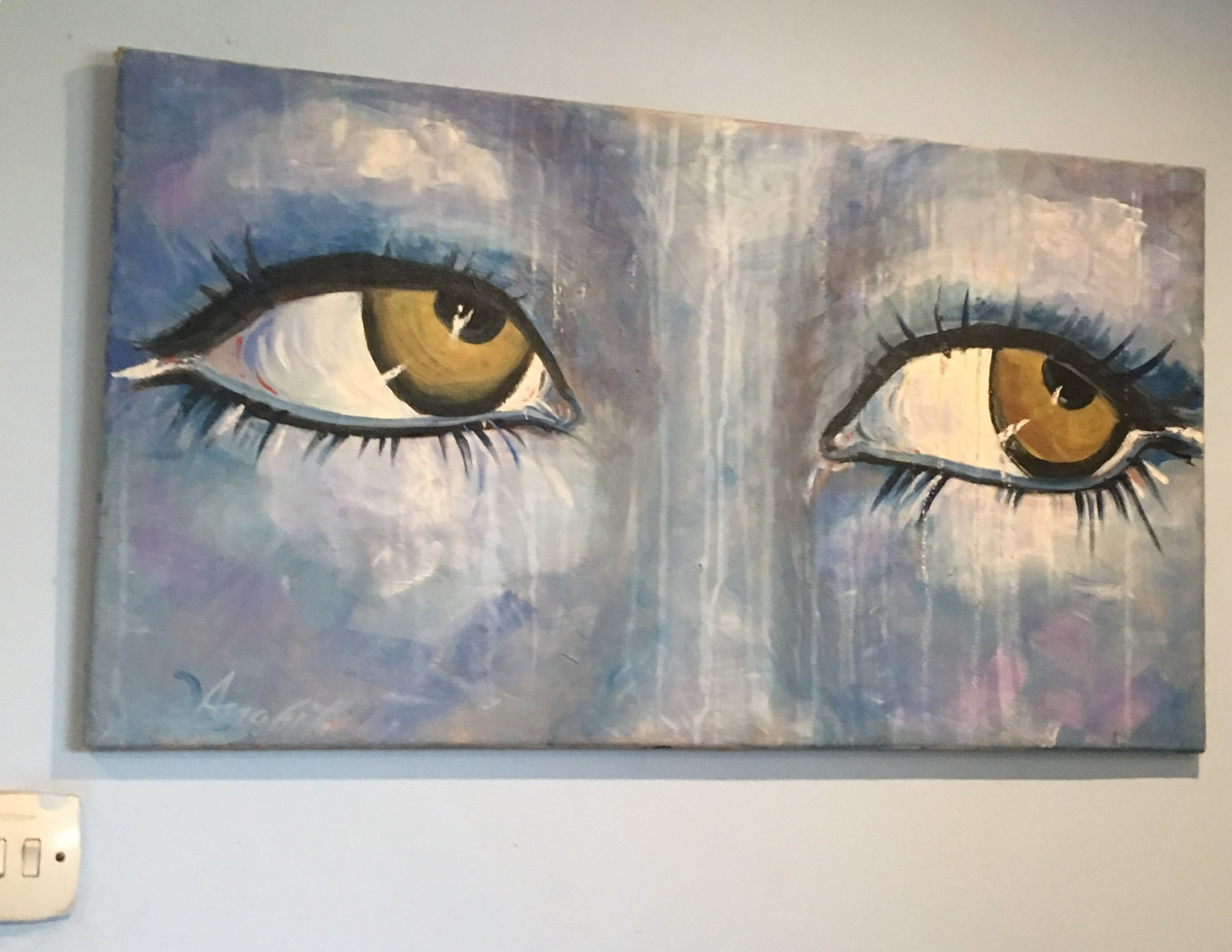 A wide painting of two amber-gold eyes with long dark lashes emerging from a wet-looking ground of blues, mauves and dripping whites