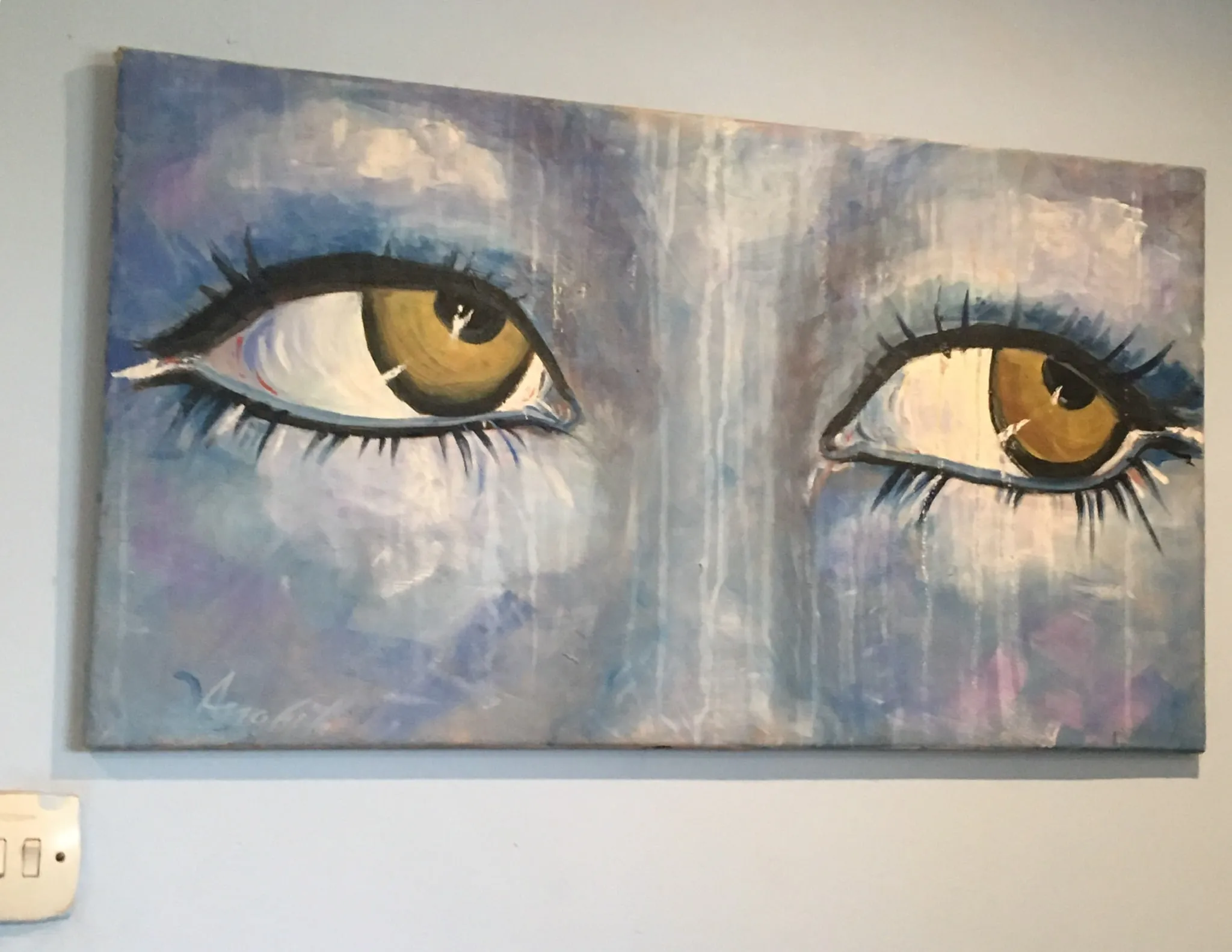 A wide painting of two amber-gold eyes with long dark lashes emerging from a wet-looking ground of blues, mauves and dripping whites