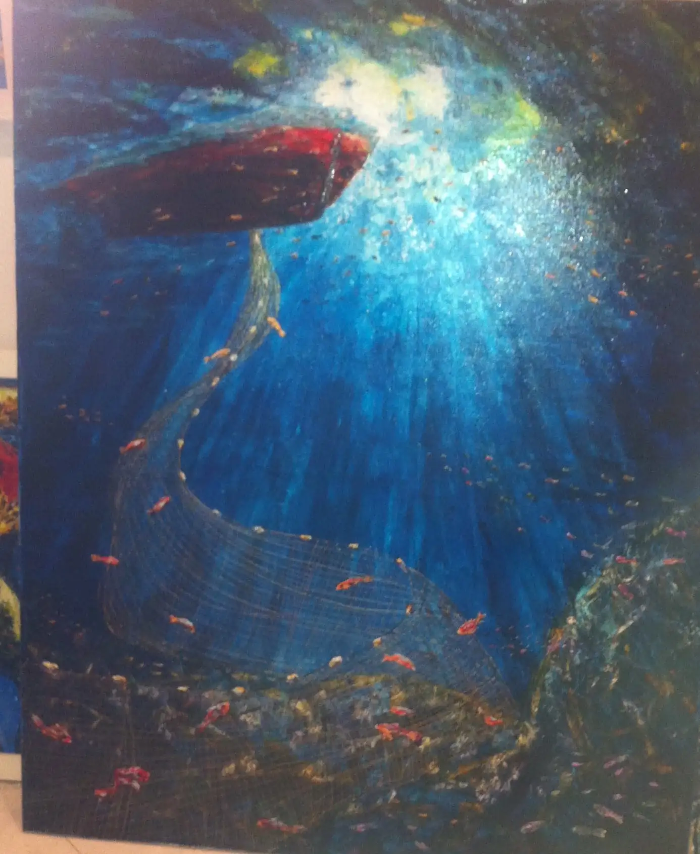 Underwater view in deep blue with a dark red boat at the surface, shafts of sunlight breaking through, a fishing net curving down and small bright fish drifting past.