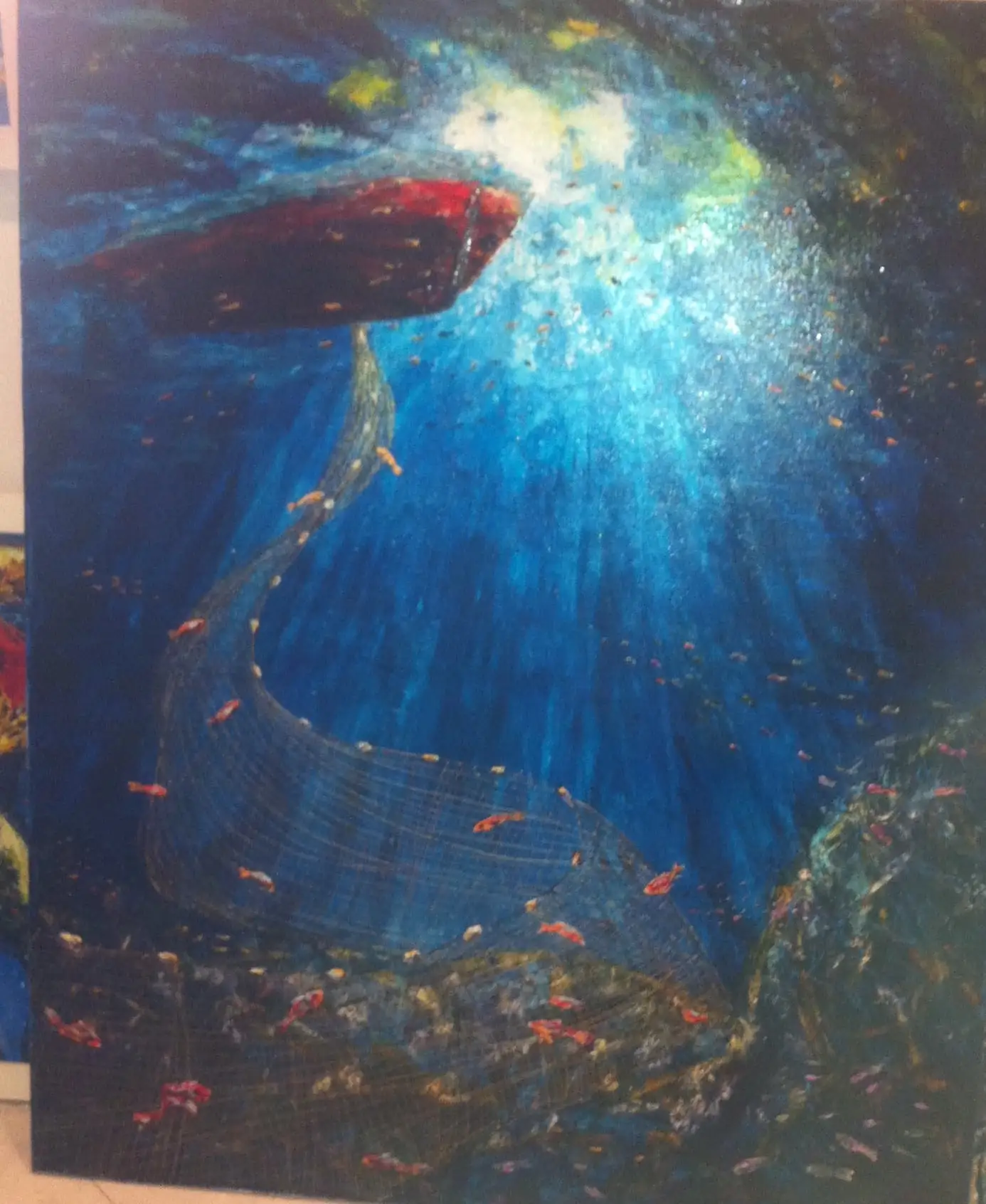 Underwater view in deep blue with a dark red boat at the surface, shafts of sunlight breaking through, a fishing net curving down and small bright fish drifting past.