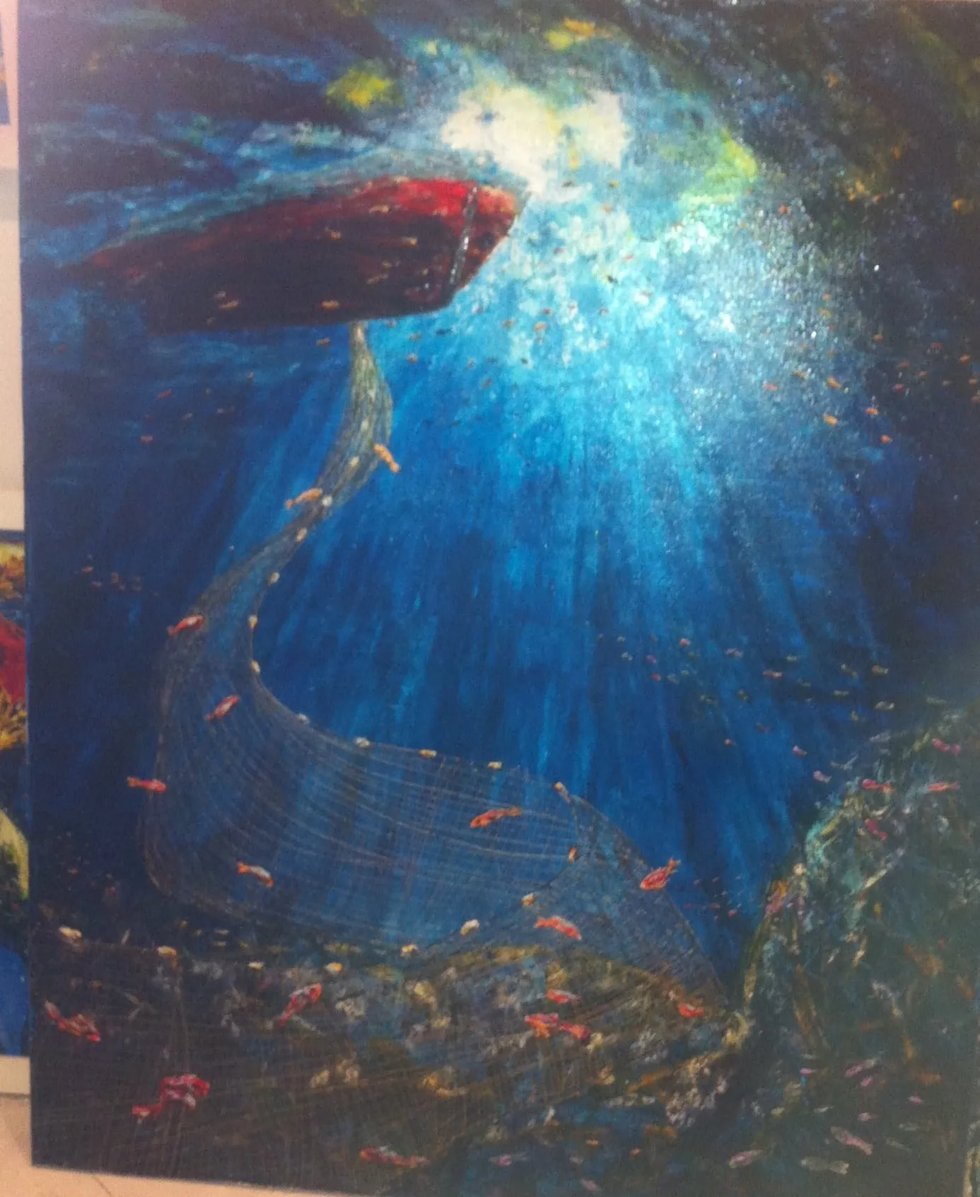 Underwater view in deep blue with a dark red boat at the surface, shafts of sunlight breaking through, a fishing net curving down and small bright fish drifting past.