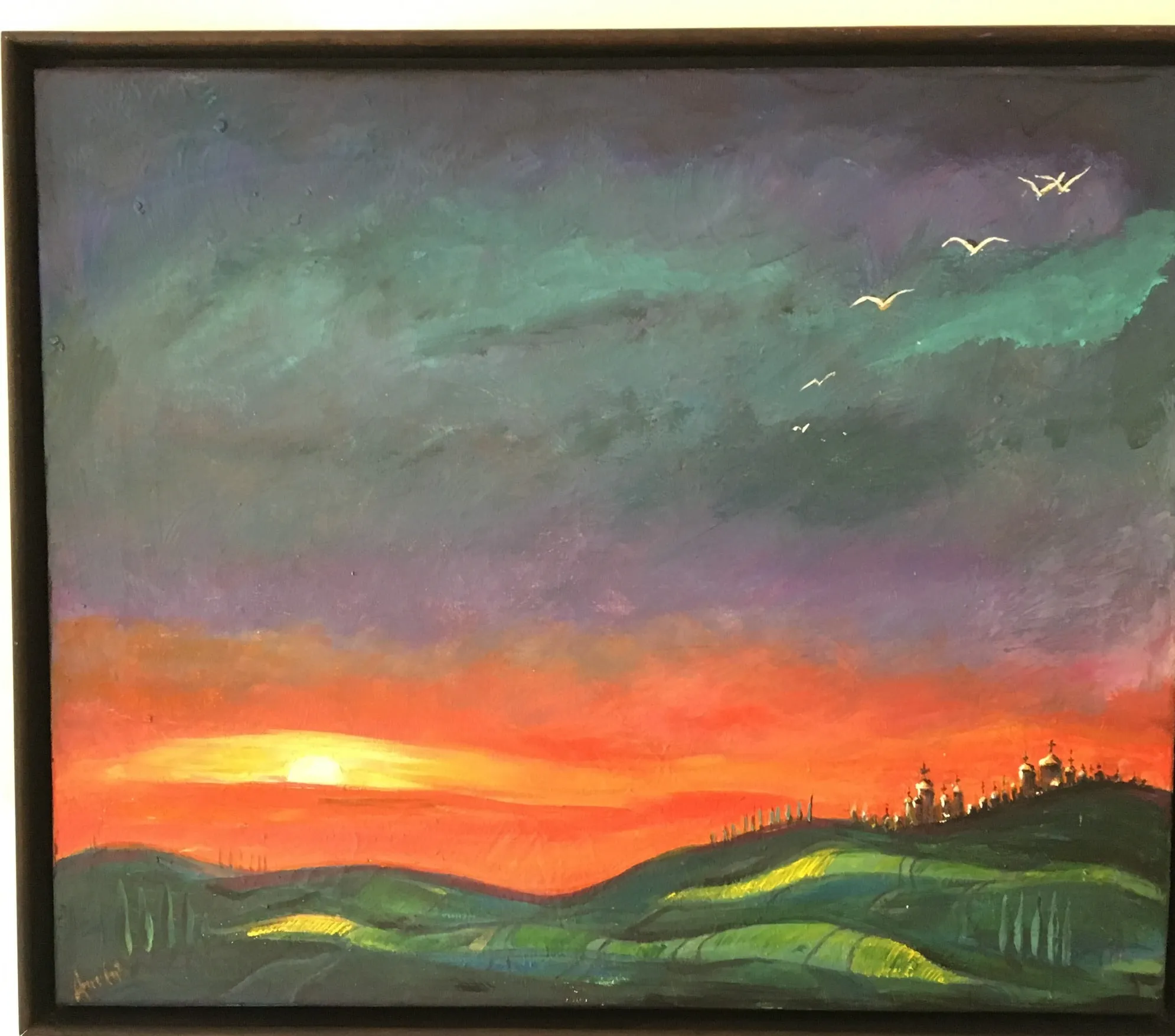 A dusk landscape with a low sun on the horizon in a broad orange and vermilion band, a purple and green sky above with a small skein of white birds, rolling green fields in the foreground and a distant hilltop crowned with a cluster of small domed buildings.