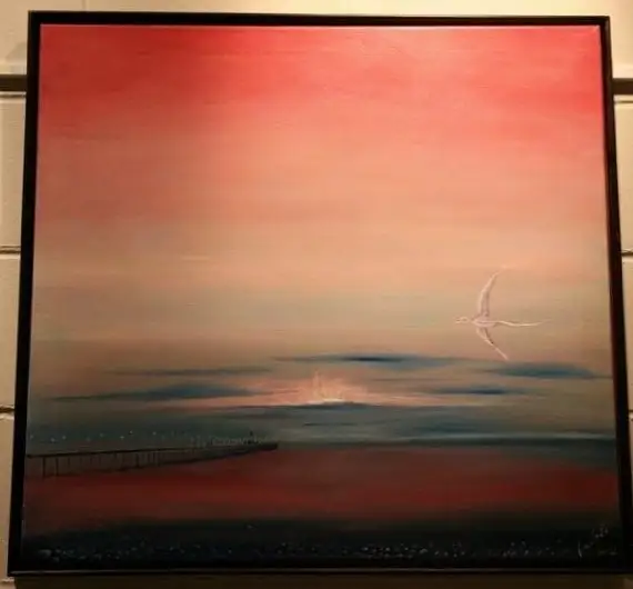 A wide coral and rose sky over a dark still sea, a low sun setting behind a distant pier, and a pale bird gliding at upper right