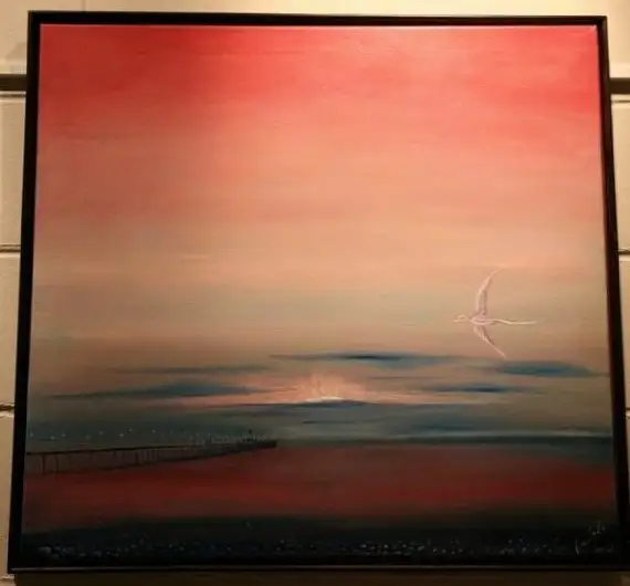 A wide coral and rose sky over a dark still sea, a low sun setting behind a distant pier, and a pale bird gliding at upper right