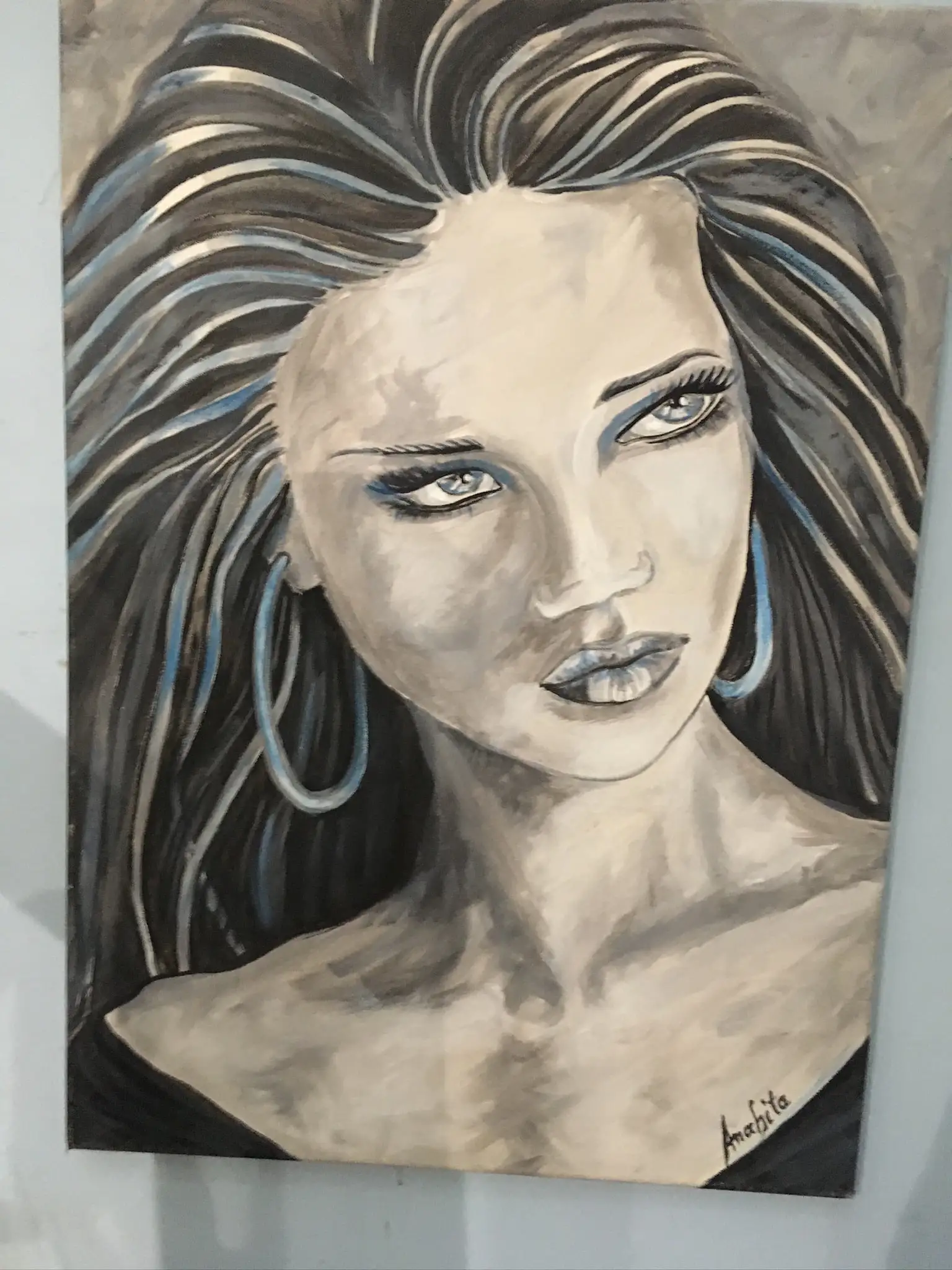 A large stylised portrait of a young woman with dramatic black hair streaked with electric blue and cream, ivory skin, cobalt-lidded eyes and a big blue hoop earring, painted in warm greys and cobalt on canvas.