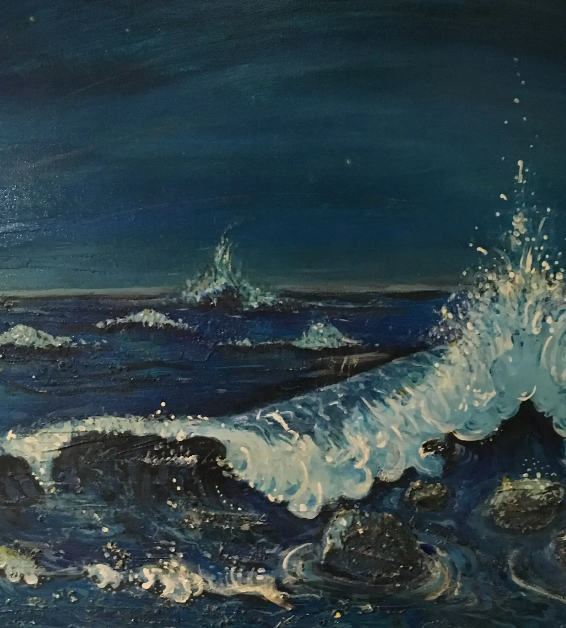 A dark night sea in deep blues and near-black, a white wave breaking over foreground rocks with spray leaping to the right under a midnight sky faintly touched with stars