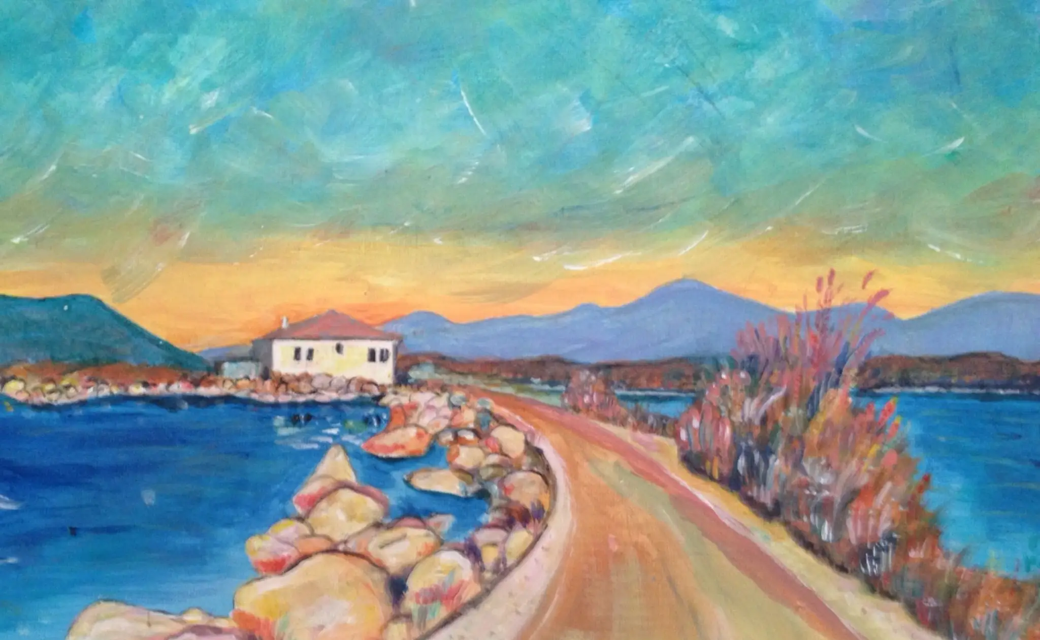 Coastal road curving into the picture beside a deep blue bay of pale rocks, a small white house with a red roof, mountains and an orange band of sunset under a green blue sky